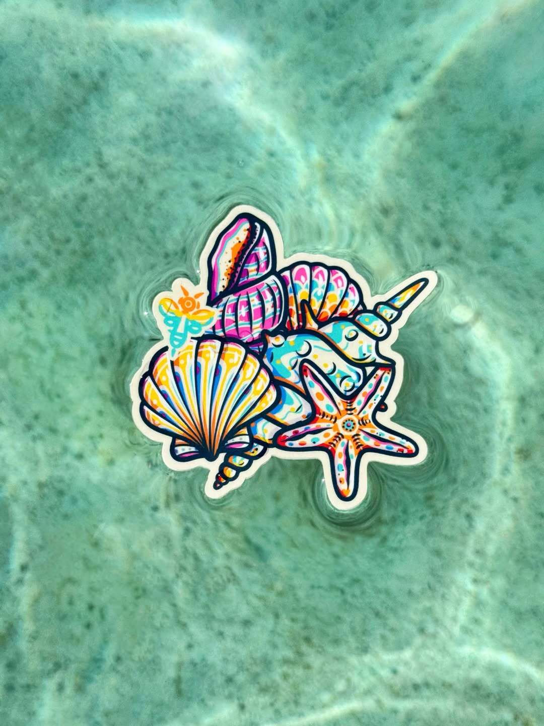 A sticker featuring colorful seashells and a starfish floating on water, shown in image_4e5a38.jpg.