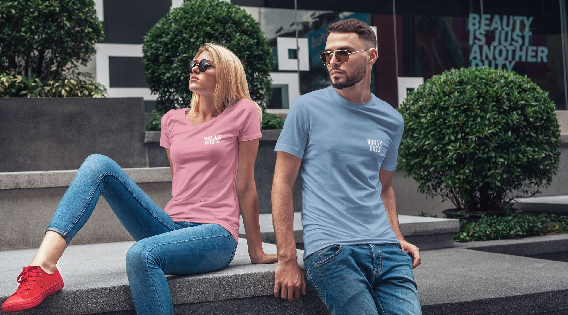 Urban Buzz Coffee promotional banner featuring a man and a woman wearing t-shirts with the Urban Buzz Coffee logo, showcasing branded apparel in a modern lifestyle setting.
